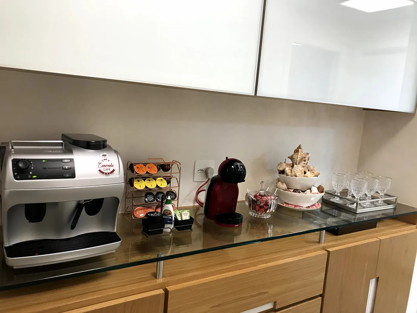 Bancada de vidro com máquina de café, taças e um bolo decorado